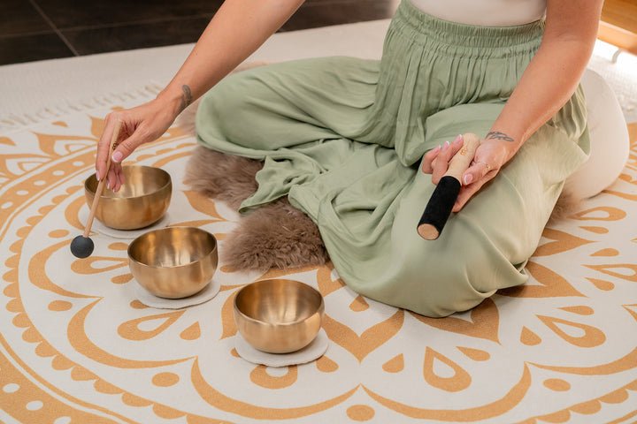 Close-up of a single singing bowl from the set being struck with a mallet.