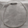 Drum head with Evans logo on a white cloth, with a cardboard box in the background.