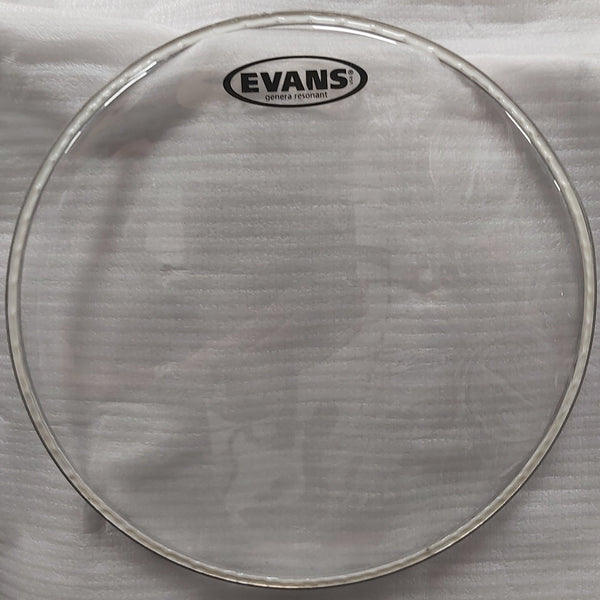 Drum head with Evans logo on a white cloth, with a cardboard box in the background.