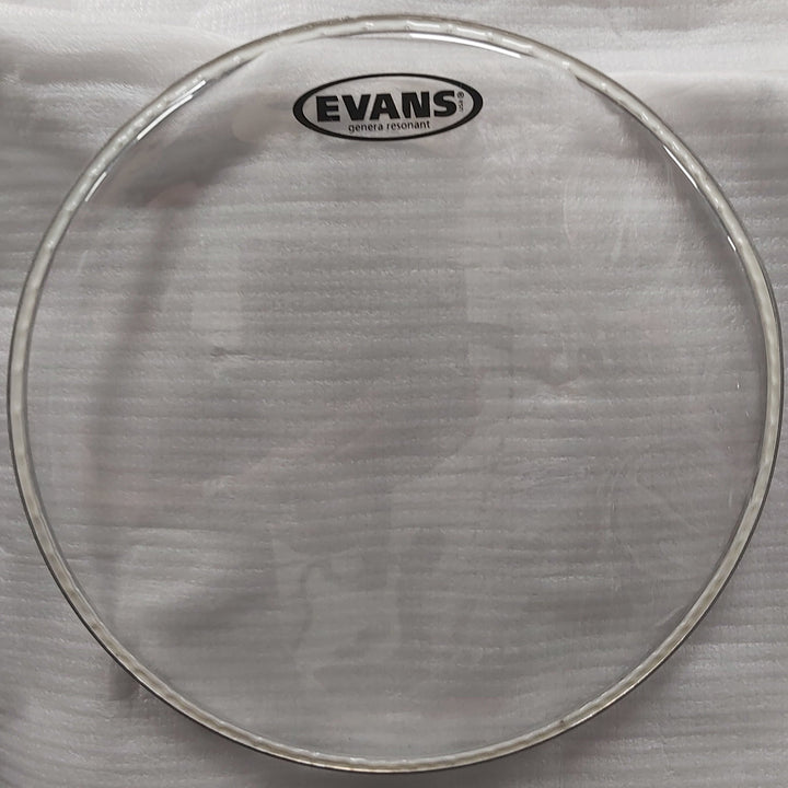 Drum head with Evans logo on a white cloth, with a cardboard box in the background.