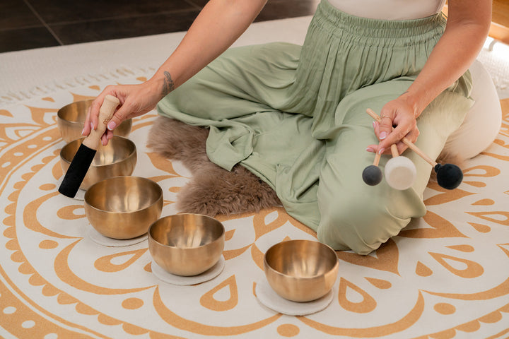 Close-up of a single singing bowl from the set with mallet and felt coaster.